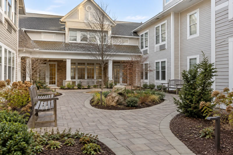 Enclosed accessible courtyard with paved walking path and benches, sparse natural plants
